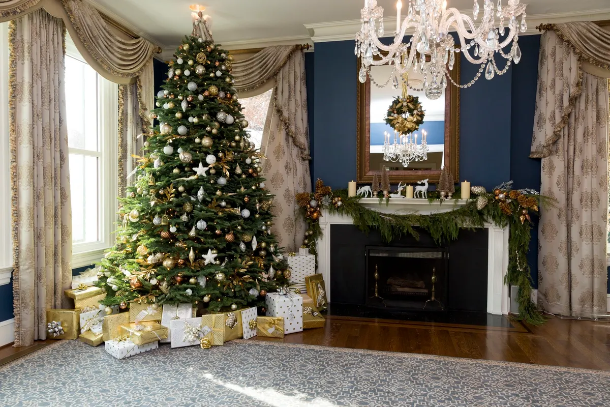 Navy room with a white mantel carrying an evergreen garland, pinecones, candles and white deer figures under a mirror with a wreath