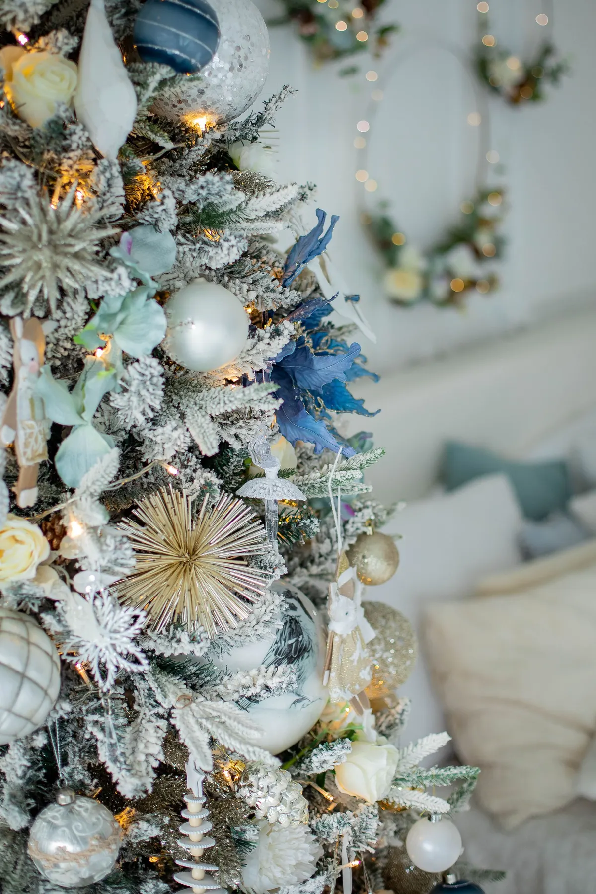 Flocked tree with white, silver and dark blue balls, cream roses, starbursts and warm lights