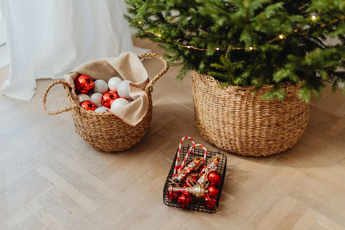 Green tree standing in a large woven basket beside a smaller basket of red, white and silver balls