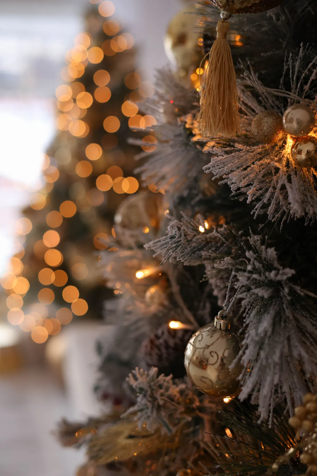 Flocked branches with gold balls, one long gold tassel, brown pinecones and gold leaf sprays under warm lights