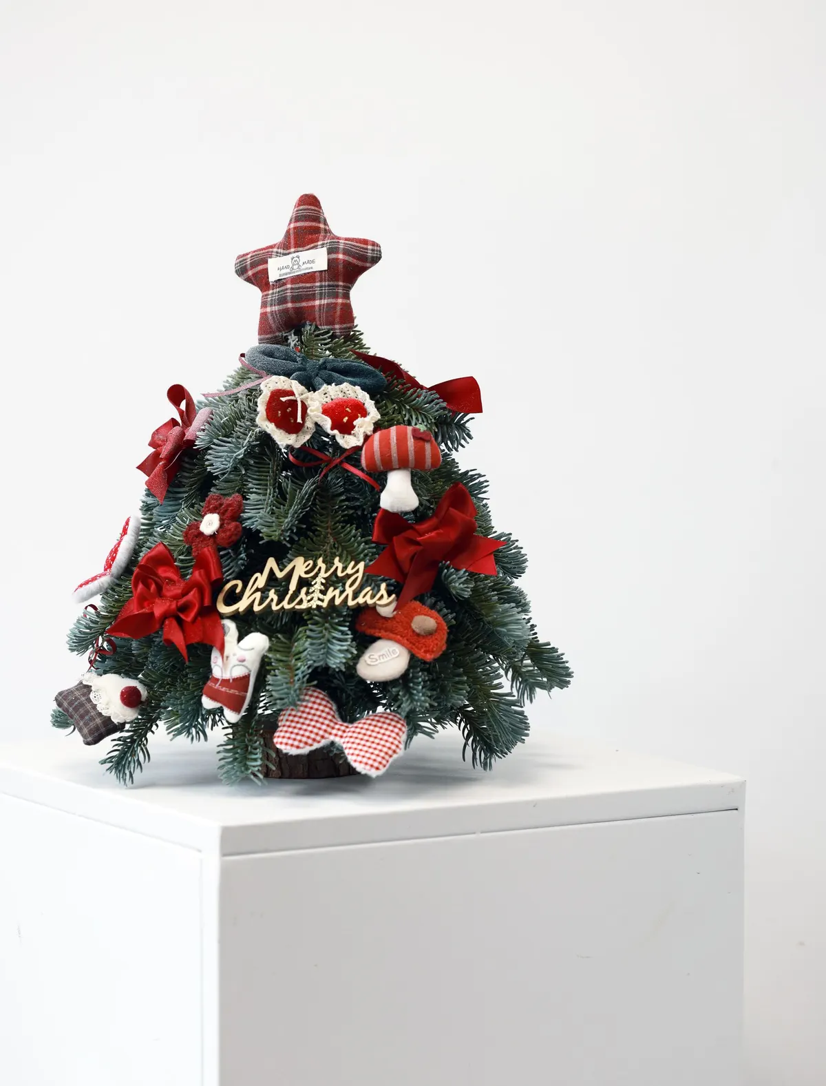 Small tabletop tree with fabric ornaments: red hearts, mushrooms, ribbon bows and a red plaid star topper