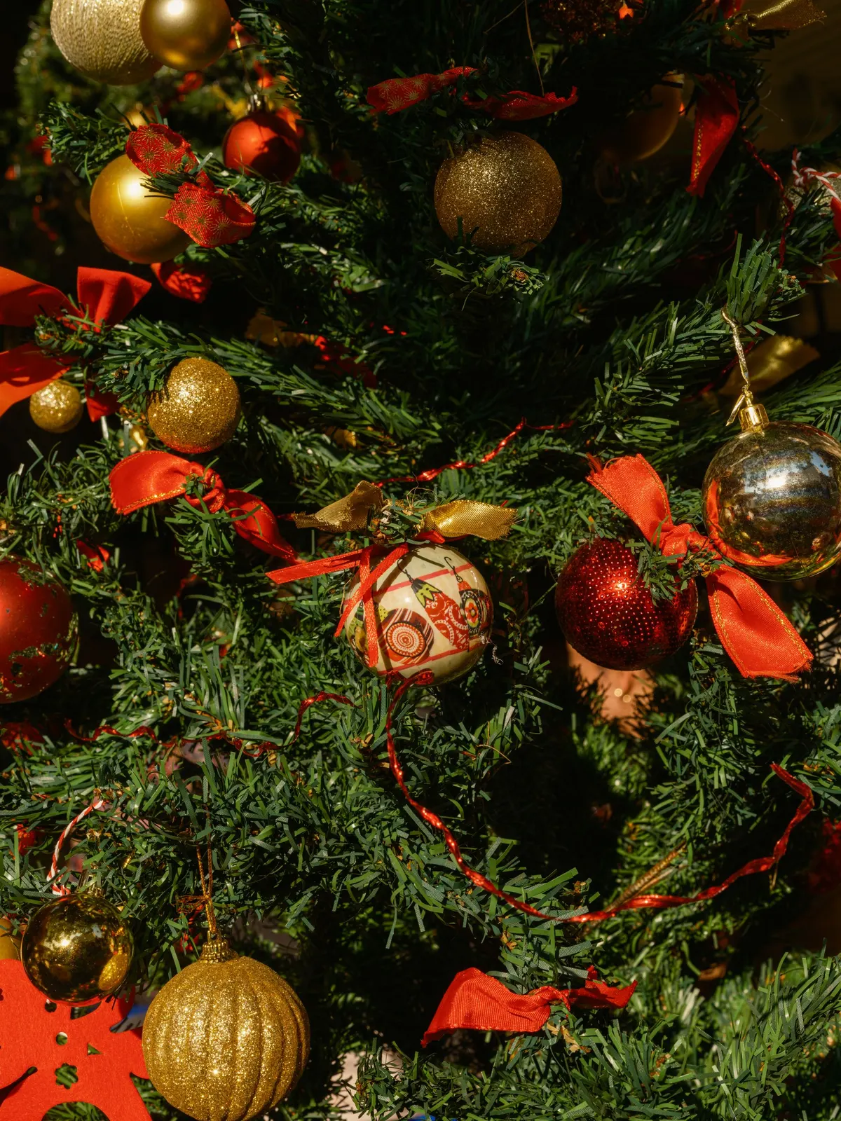 Green branches with red and gold balls, red and gold-edged bows and a thin red metallic garland