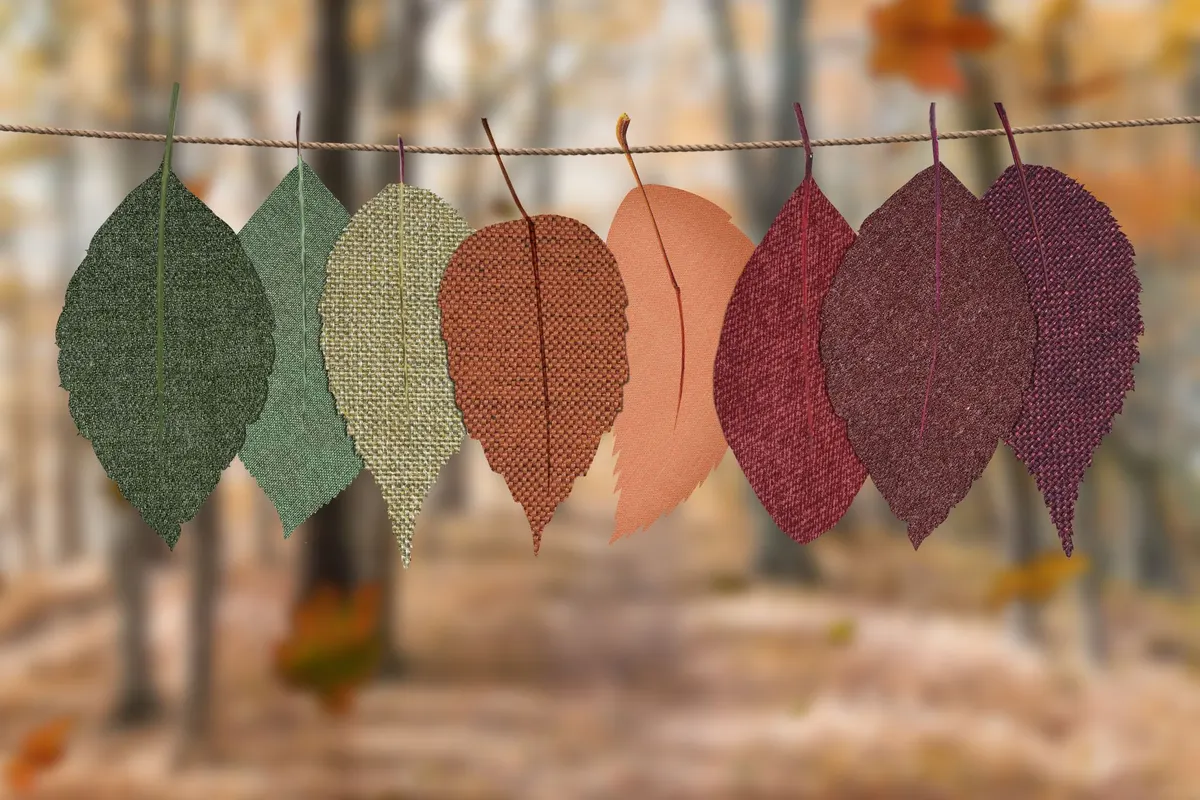 Eight fabric autumn leaves in rust, sage and burgundy hanging from a tan twisted cord