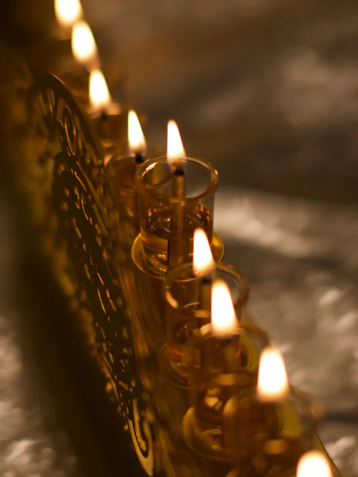 Gold oil menorah with clear glass cups of amber oil and nine small flames on foil