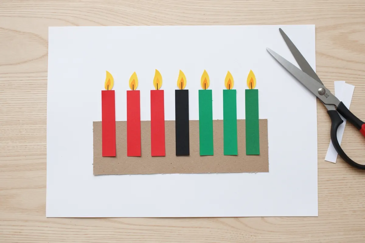 Child's paper kinara craft with three red, one black and three green paper candles on kraft paper