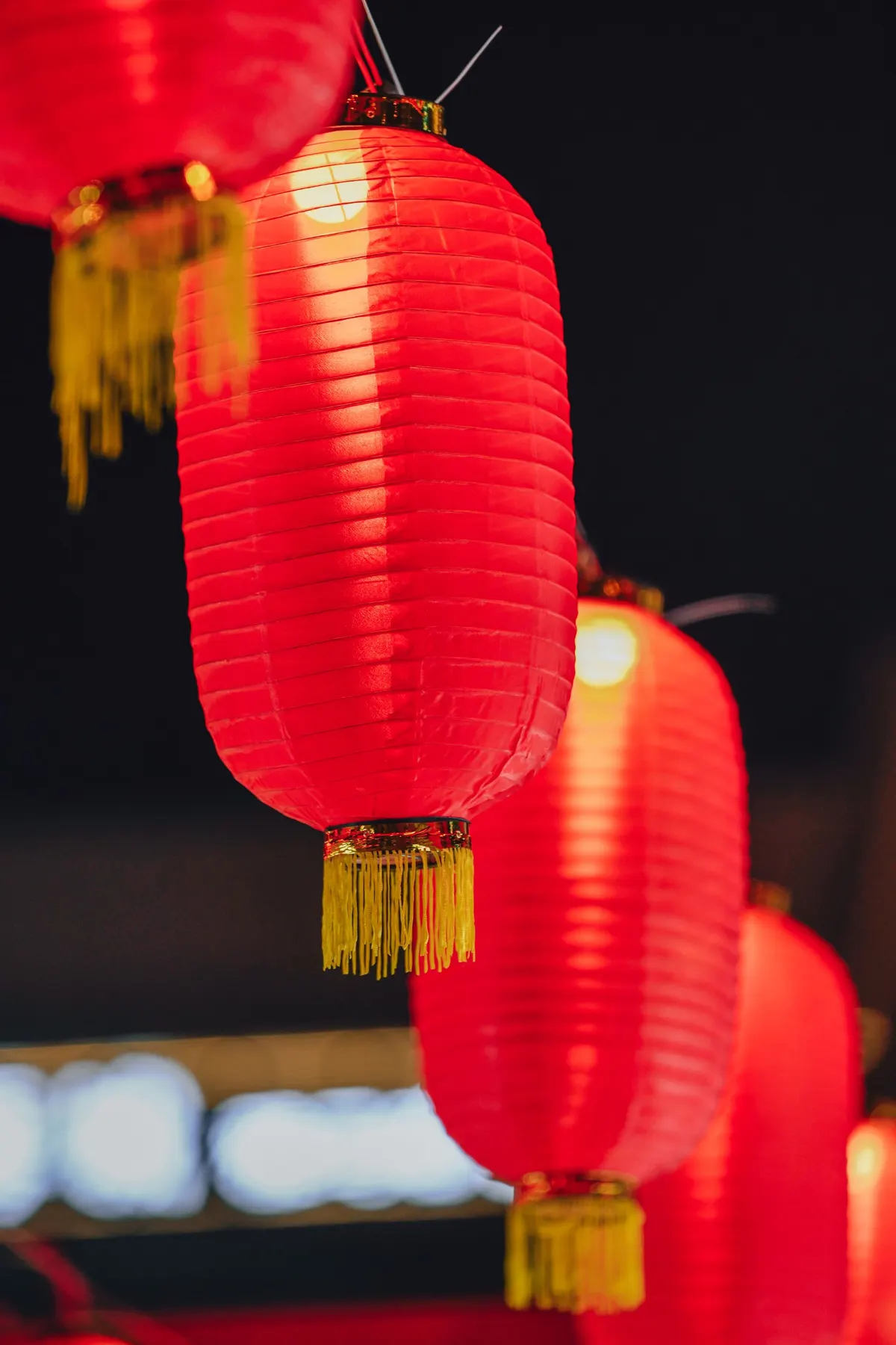 Several red lanterns with gold caps and yellow tassels glowing against a dark background