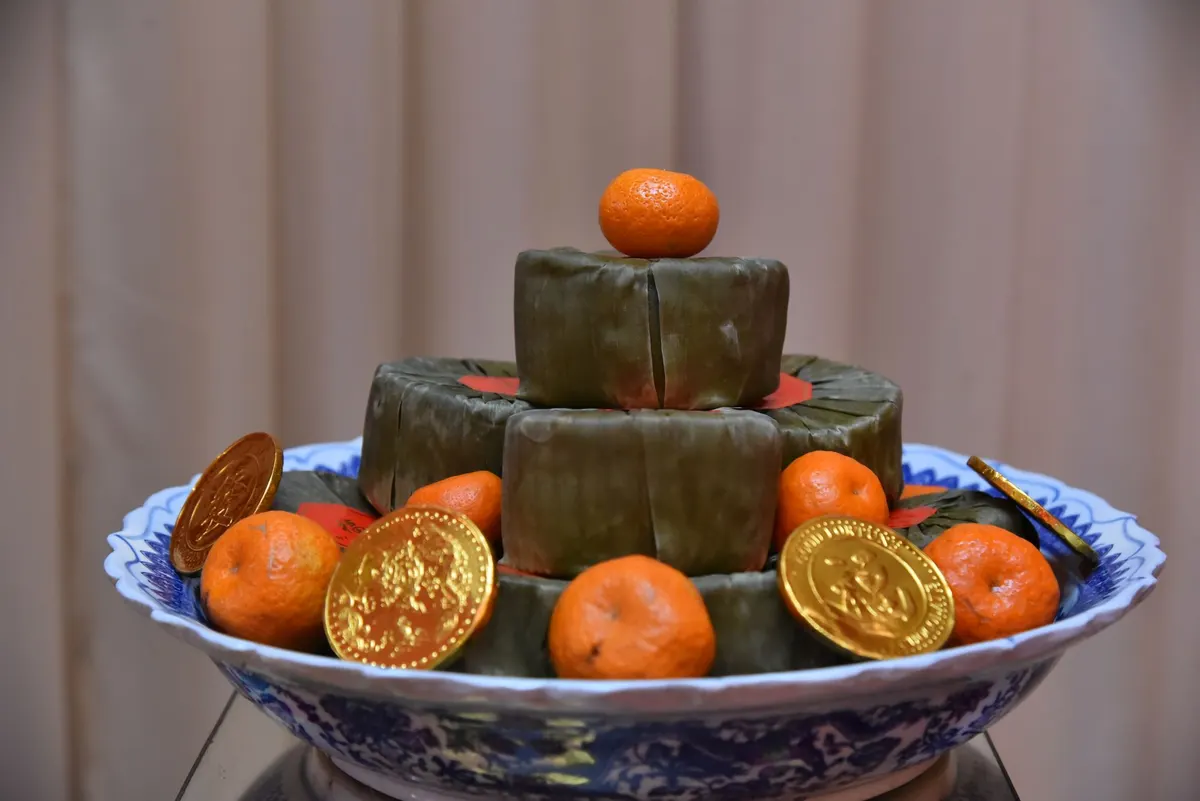Blue and white platter with leaf-wrapped parcels, six mandarins and four gold coin decorations