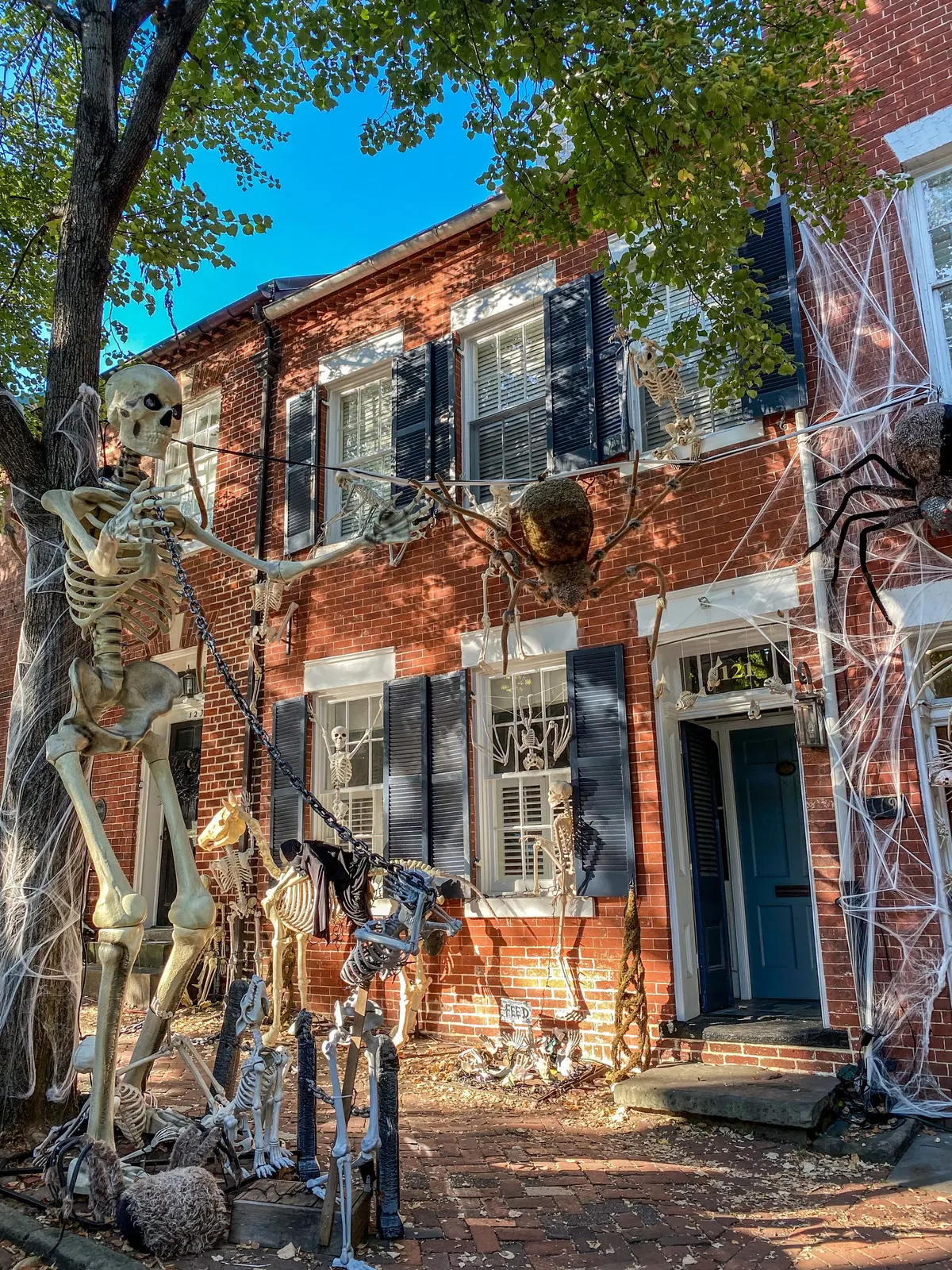 Red brick house with a blue door, a giant ivory skeleton, many small skeletons and big dark spiders