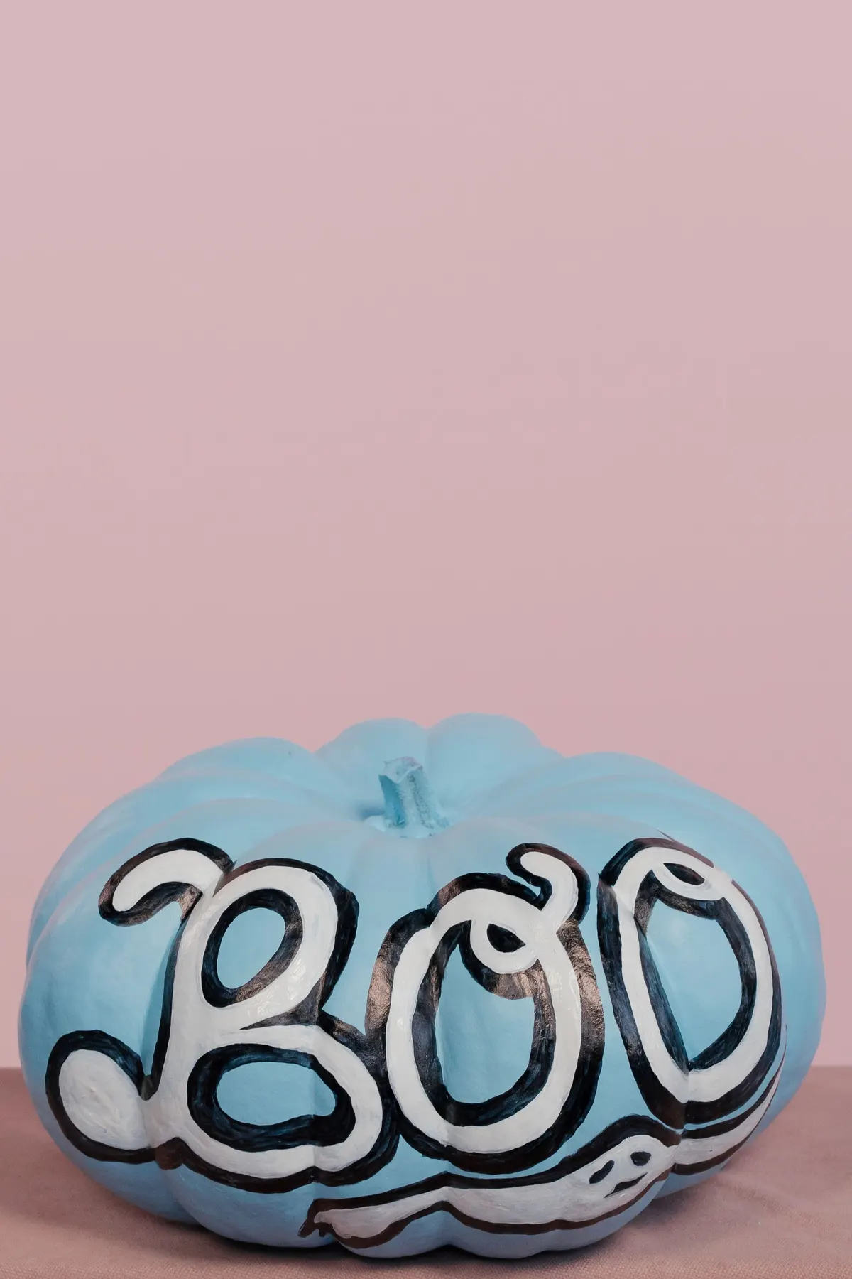 Pale blue ribbed pumpkin with large white BOO letters outlined in black and a long white ghost shape underneath