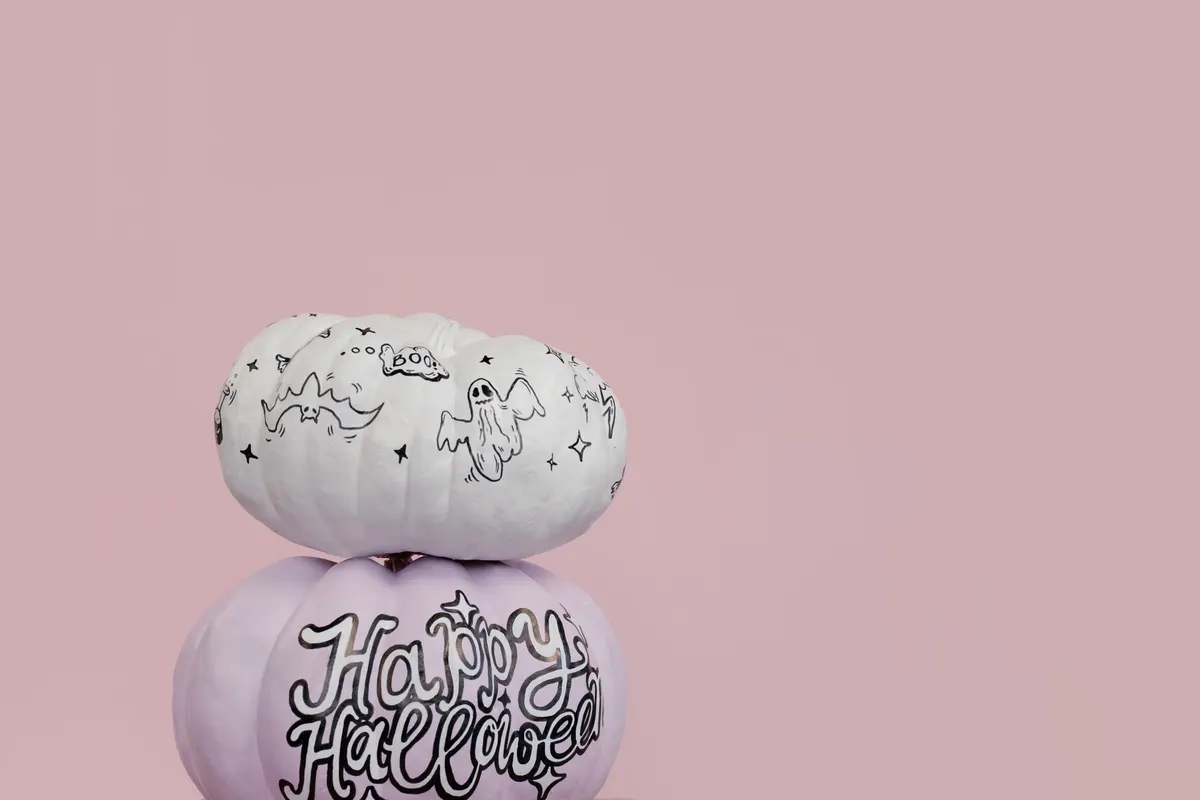 Pale lavender pumpkin with black-outlined cursive Happy Halloween lettering and sparkles under a white pumpkin