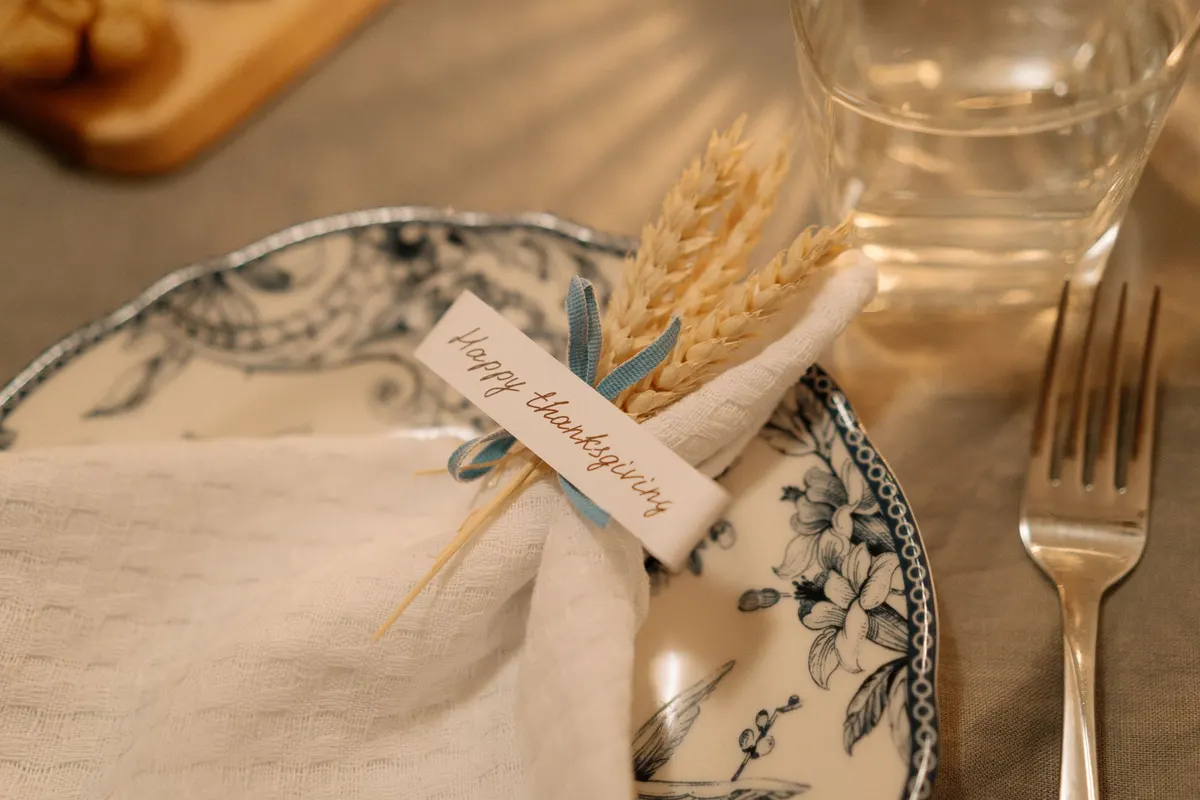 Floral china plates with a white napkin, a dried wheat bundle and a handwritten thanks tag