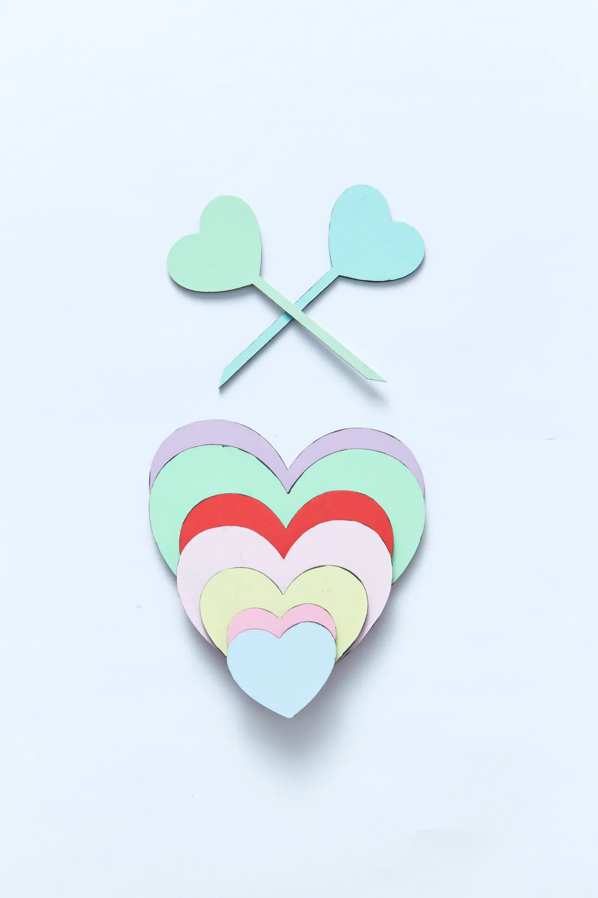 Seven stacked pastel paper hearts in lavender, mint, red, pink and blue with two heart-topped paper stems